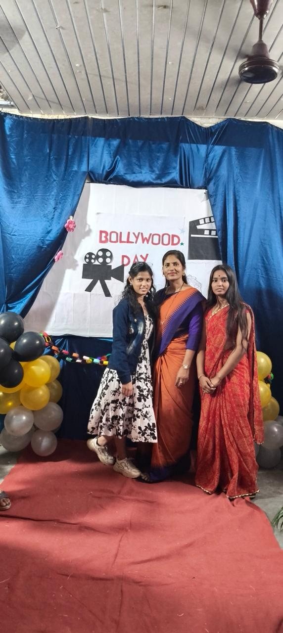 Three participants posing at the Bollywood Day backdrop