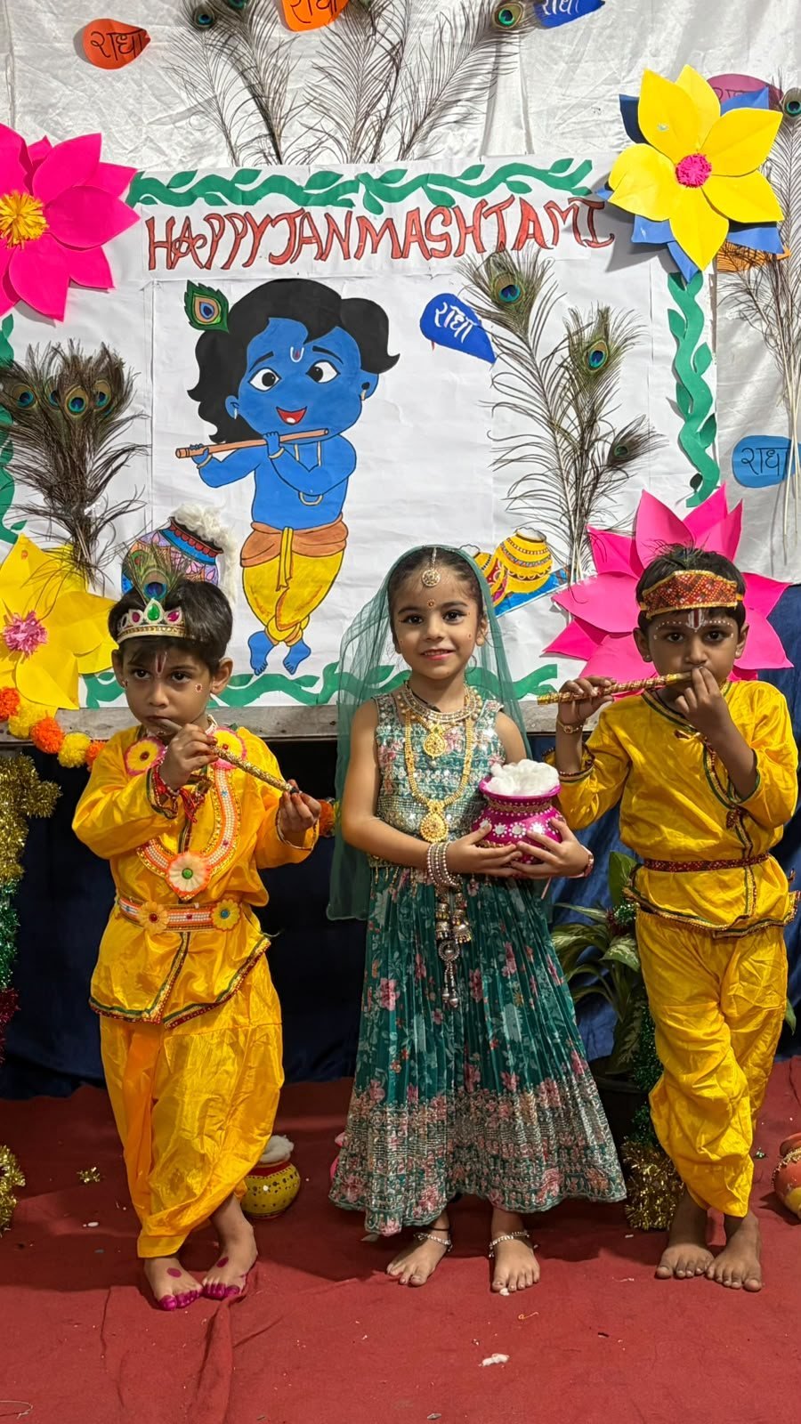 Three young students in Krishna and Radha costumes with a matki